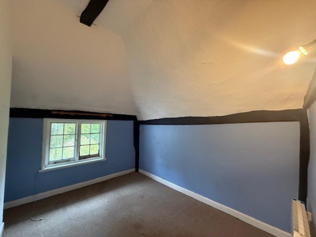 Lot: 168 - A PAIR OF THATCHED COTTAGES IN NEED OF IMPROVEMENT - 50 Abbey Street bedroom two with window and vaulted ceiling